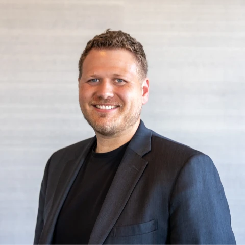 Jason Hawronsky, Founder of Monarch Game Studios, smiling in a navy blazer over a black tee