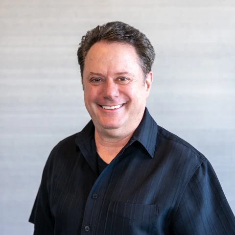 Louis Castle, CEO of Monarch Game Studios, smiling in a dark button-up shirt